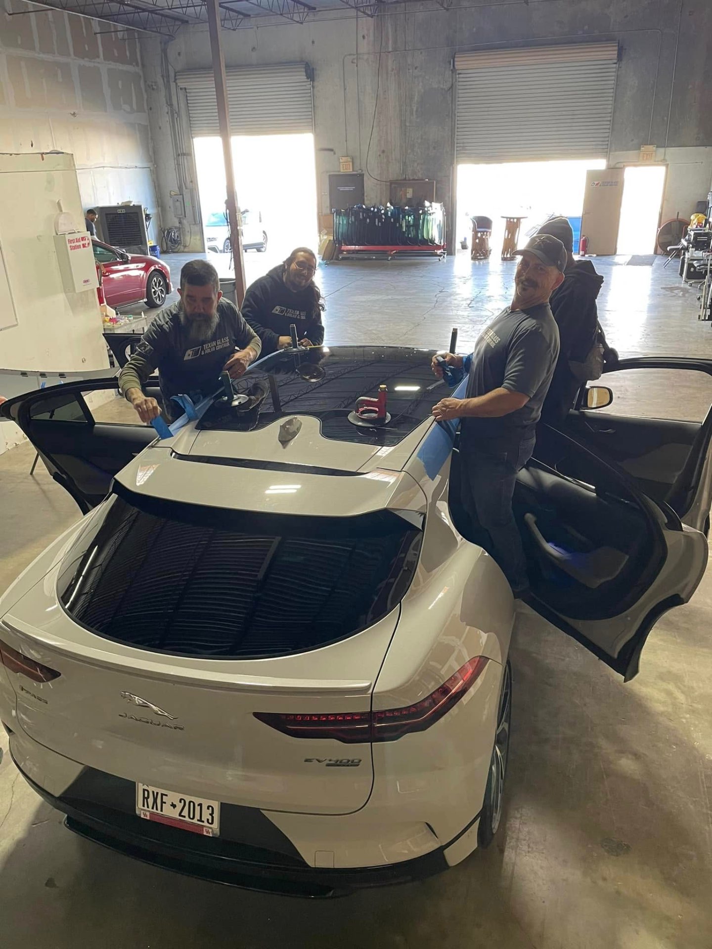 Woodlands Auto Glass team performing a windshield replacement on a Jaguar EV